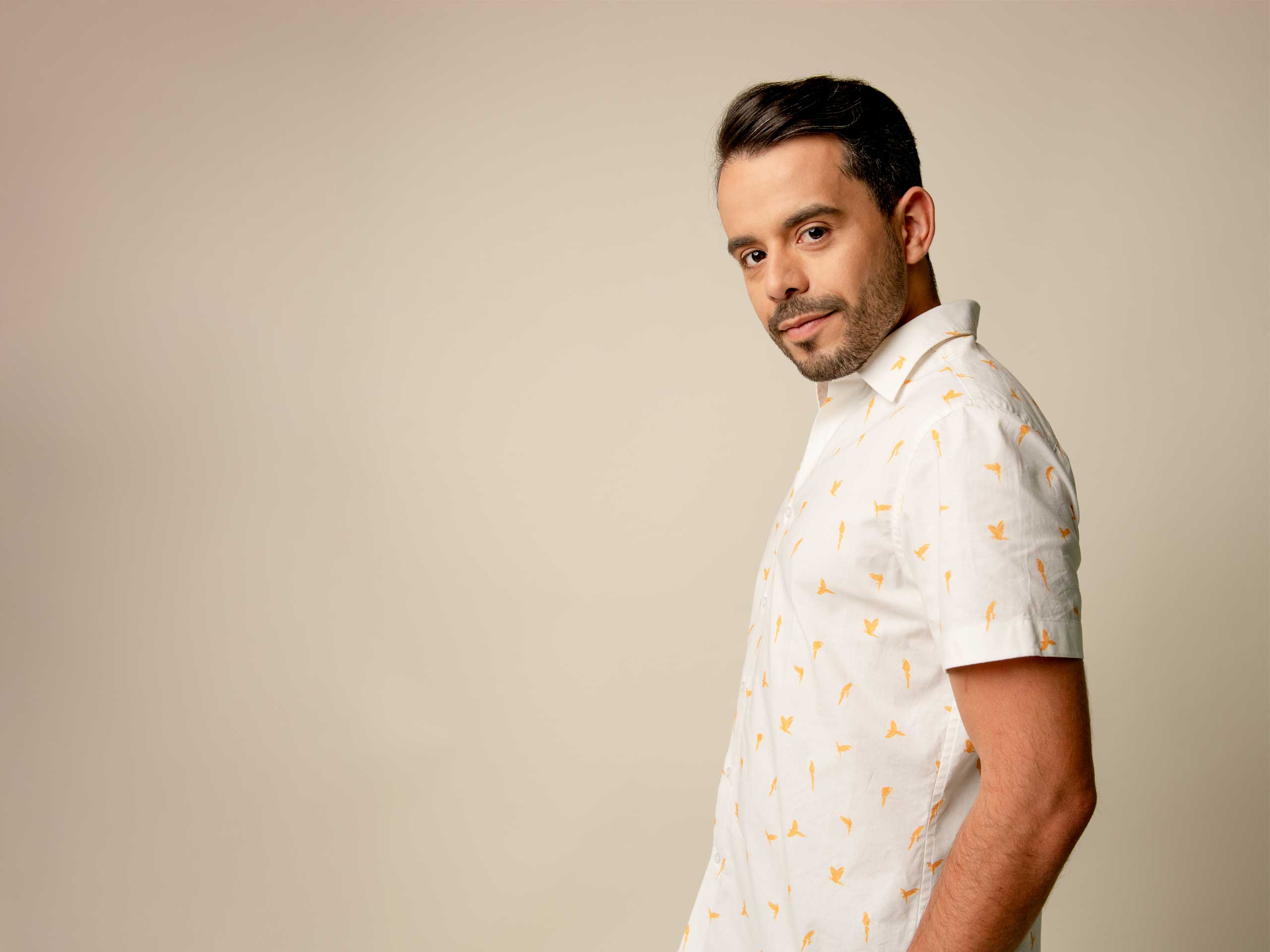 Man wearing a white patterned shirt against a beige background